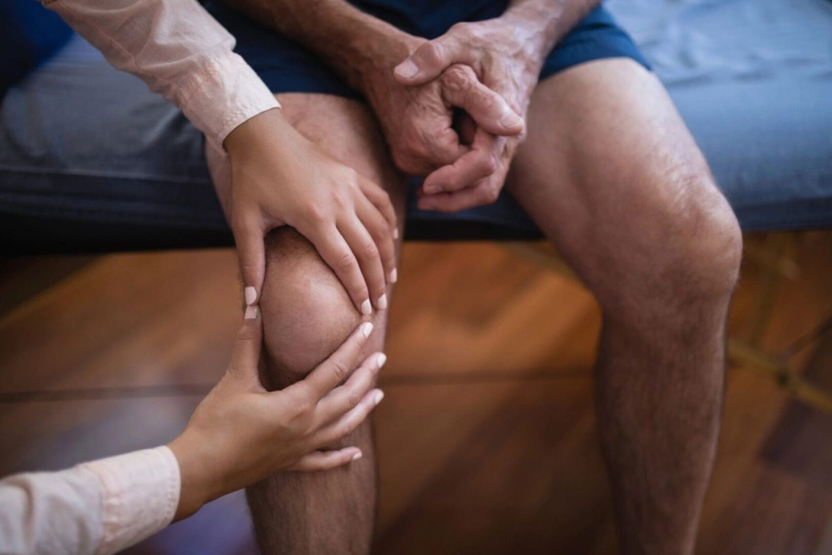 A person holding their knee while another holds his hand.