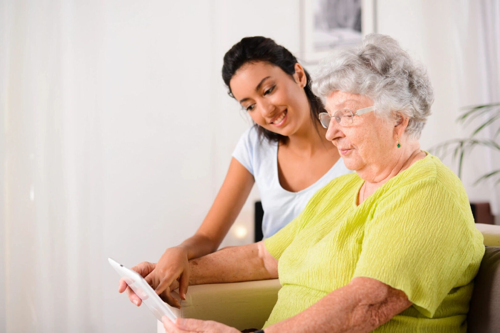 A woman and an older person looking at something on a tablet.