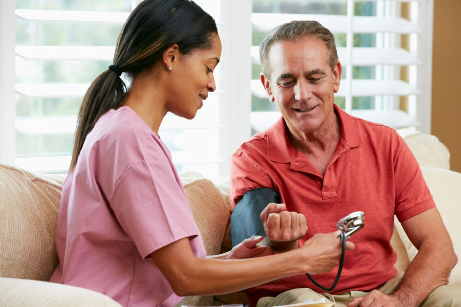 A nurse checking the blood pressure of an older man.